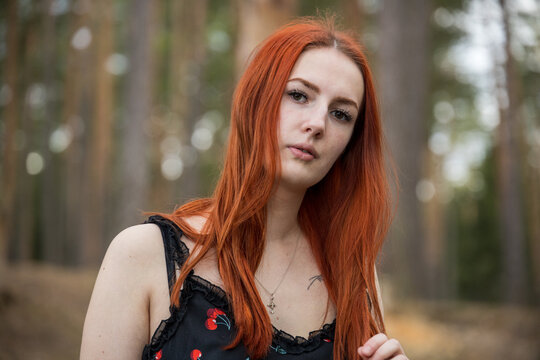 Red-haired woman stands in a forest