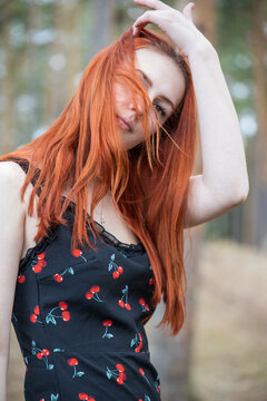 Red-haired woman poses softly in a forested setting
