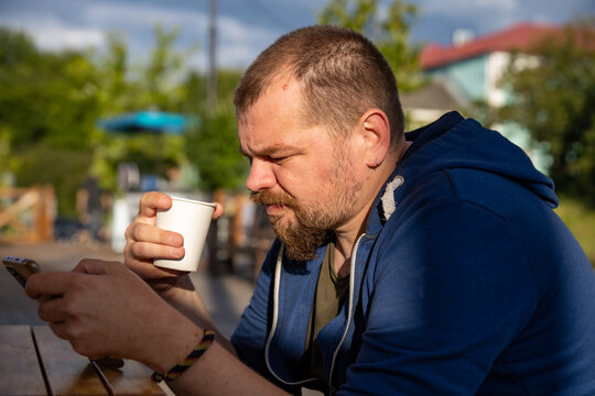 Man sips coffee while scrolling phone