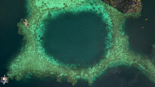 Cinematic aerial approach to Twin Lagoon in Coron, Philippines, revealing emerald and turquoise waters surrounded by towering limestone karst formations.