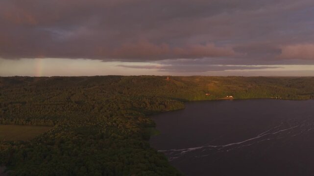 Aerial view of Himmelbjerget overlooking the lake and dense forest under a sunset sky with a rainbow in Skanderborg Municipality, Skanderborg Municipal, Denmark.