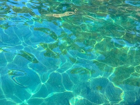 Top view transparent turquoise sea water with sun reflections