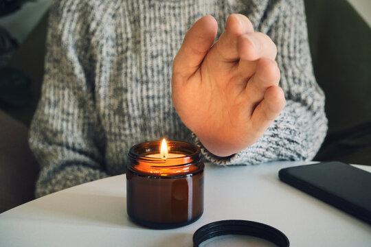 Person's hand feeling heat from burning candle for warmth and comfort