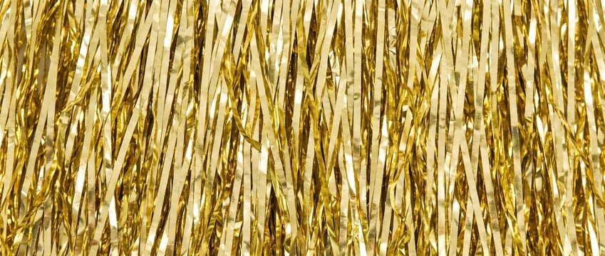 Close up of gold tinsel fringe texture. Shiny metallic vertical strips background. Sparkling foil strands for festive party decoration