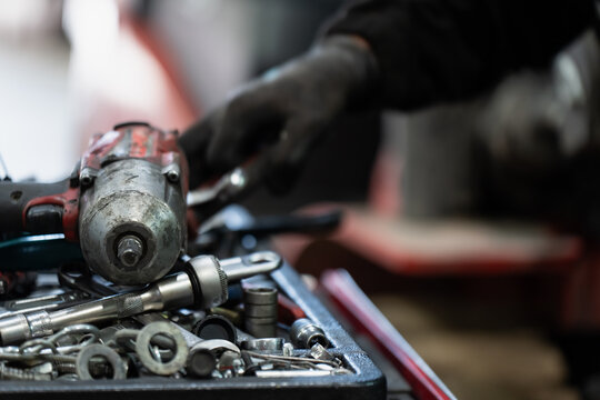 Sockets and drive extensions surround a worn impact wrench in a mechanic's tool tray, representing fastener service equipment and workshop tool management during machinery repair