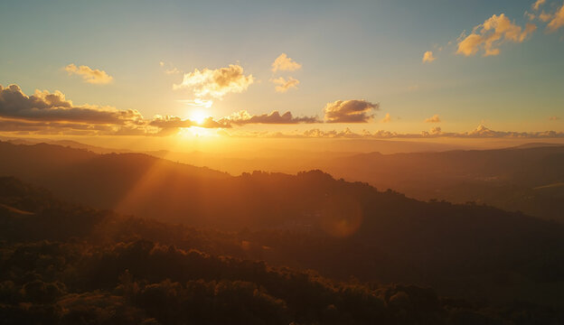A picturesque sunset over a mountain range, with the sun dipping below the peaks and painting the sky in brilliant colors.