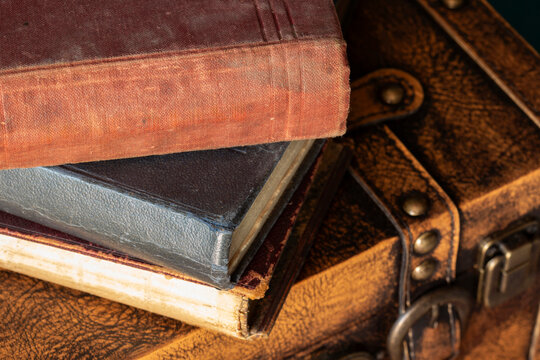 Old vintage antique books on top of a vintage leather luggage case. Vintage travel background backdrop concept.