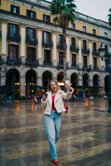 Obraz premium Excited woman taking selfie on city square, making video call, blogging influencer, 5G wireless technology, mobile app, authentic representation, digital nomad, urban travel lifestyle.