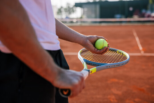 Side view of a tennis player preparing to serve on a red clay court