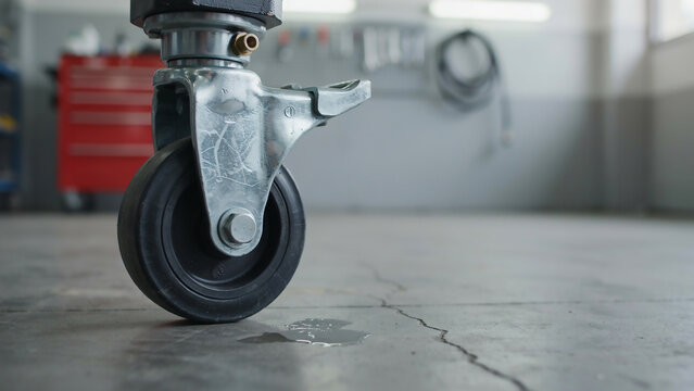 Close-up of a black caster wheel on a cracked concrete floor keywords: caster, wheel, industrial