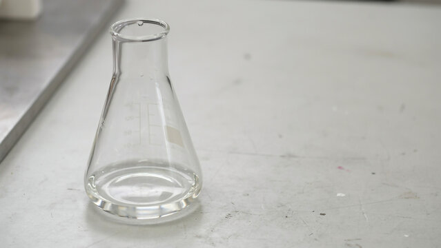 Empty erlenmeyer flask with graduations on a white surface keywords: erlenmeyer flask