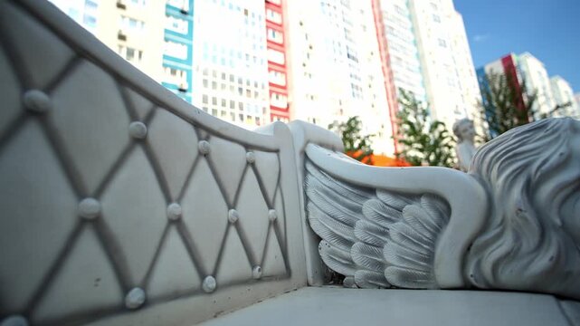 White ornamental carriage details rest quietly with high rise city buildings rising behind. Elaborate carriage upholstery patterns and winged carving highlight nostalgic craftsmanship.
