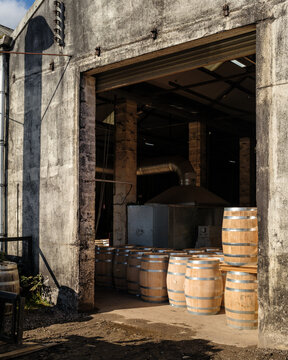 New wooden whisky barrels wait in the open entrance of a traditional cooperage located in Craigellachie, Moray, Scotland during a bright day