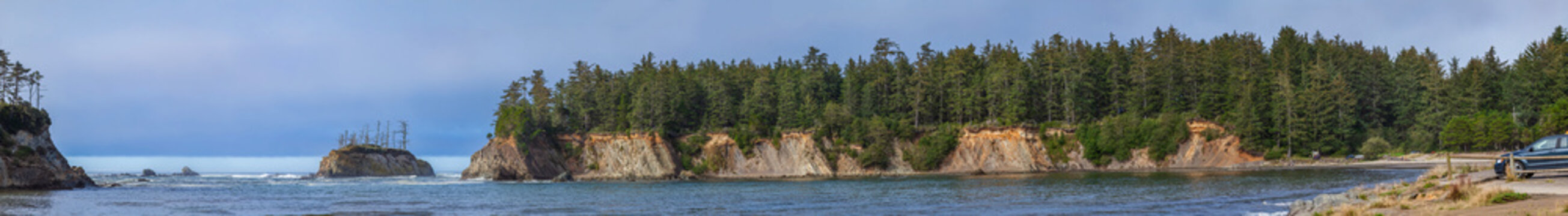 Beautiful wide panoramic view of a wild rocky ocean coast with green mountains and a small island