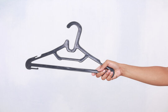 hand holding a black plastic coat hanger on a light background
