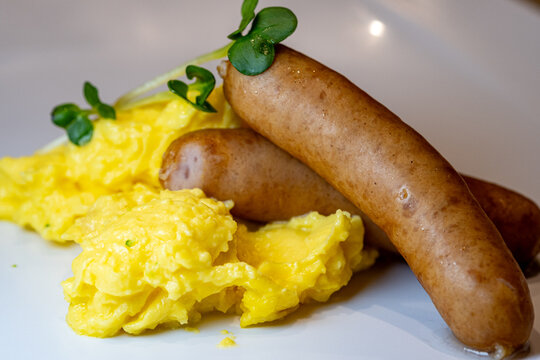 Close-up view of grilled sausage served with scrambled eggs.