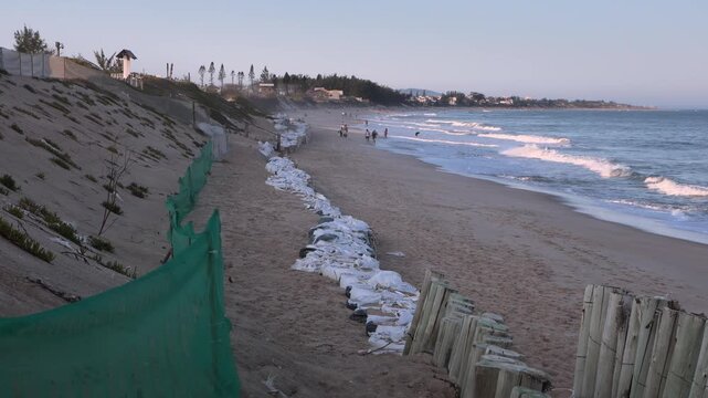 Defensive barriers made of stakes and sandbags on a beach front view
Coastal protection system with wooden stakes and sandbags against wave action
Beach erosion control barrier with sandbags and woode