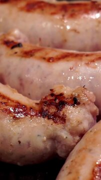 Close up video of freshly cooked sausages on a ribbed grill pan, showing golden brown crust and savory juices.