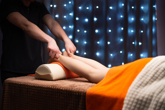 Therapist massaging client legs in wellness center