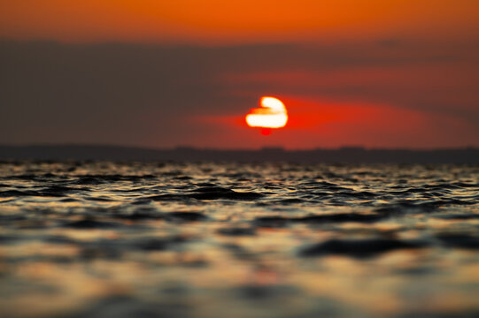 Sun setting over rippled water surface at dusk