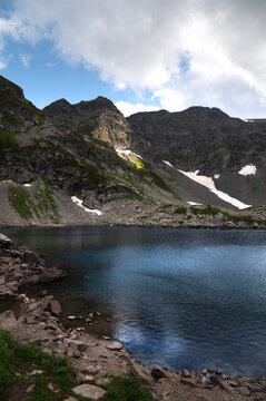Mountain lake with rocky shore and steep slopes