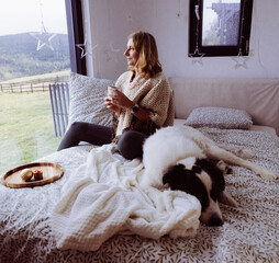 Obraz premium happy woman with dog relaxing in bed at Christmas time