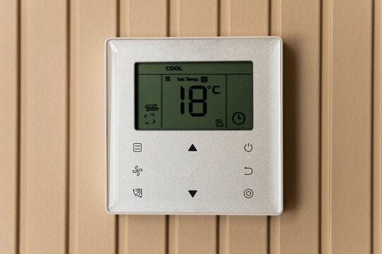 Digital Thermostat Control Panel on Wooden Wall
