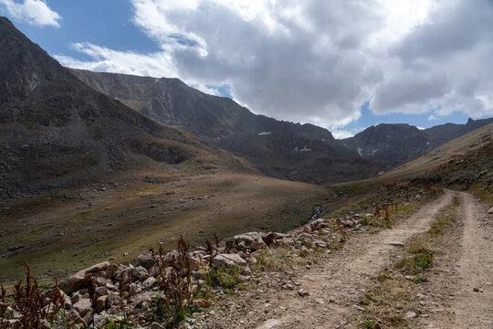 Dramatic Rocky Mountain Valley with Hiking Trail and Jagged Cliffs.