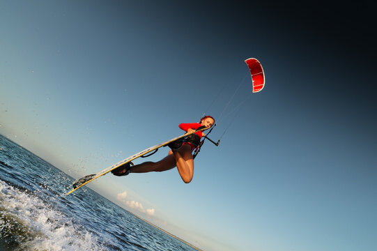 Woman kitesurfing and jumping over ocean water