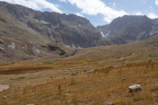 Dramatic Rocky Mountain Valley with Hiking Trail and Jagged Cliffs.