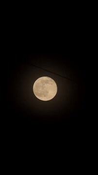 Luminous moon illuminates deep darkness during smooth astronomy timelapse. Radiant lunar surface travels steadily across pitch black heavens, evoking tranquil and mysterious celestial mood.