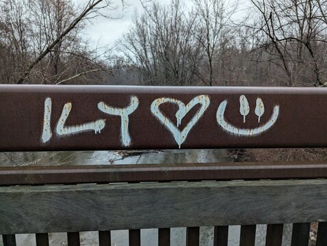 ILY (I love you) with a heart and smiley face, white graffiti on metal bridge