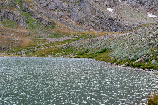 High-Altitude Mountain Lake Surrounded by Rocky Peaks and Snow Patches.