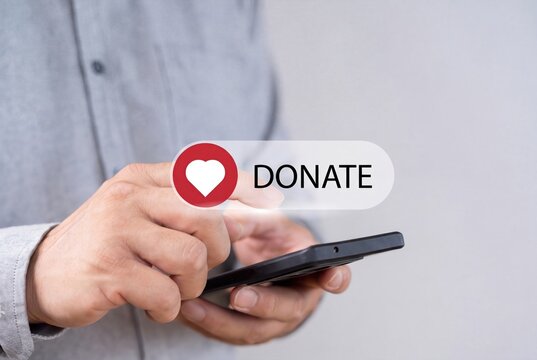 Online donation concept with heart icon, man using smartphone for digital giving, charitable fundraising and social support app.