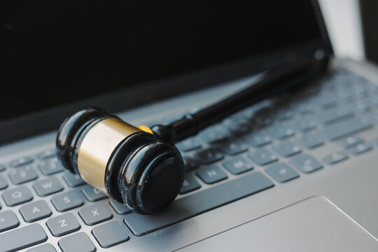 Judge's gavel resting on a laptop keyboard, symbolizing online law, digital justice, legal proceedings, legislation, court decisions, and modern legal services.