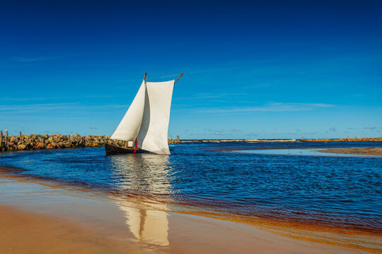 A sailboat with white sails in the beach of the Baltic sea