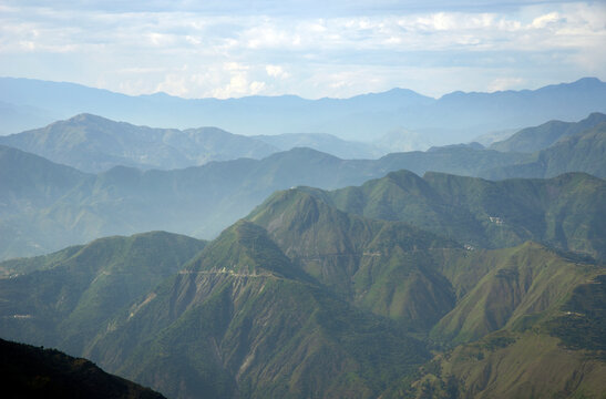 Scenic daytime view of lush green mountain slopes and distant hazy ridges in Mussoorie