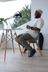 African American man wearing beanie recording in home studio with boom mic pop filter, copy space © WavebreakMediaMicro