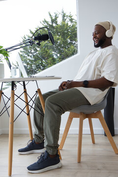 Man wearing beanie and headset recording podcast sitting at home studio with boom mic, copy space