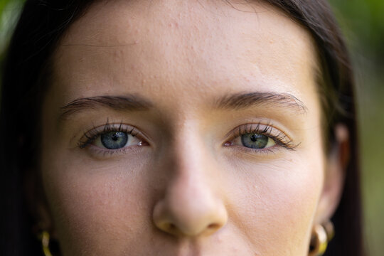 Female posing for close-up headshot outdoors in garden showing small gold hoop earrings
