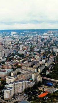 Vertical video. Saratov, Russia. Aerial panoramic sweep over the Volga River embankment, dense Soviet-era residential blocks and the historic city center under an overcast sky. Drone footage. Rich co