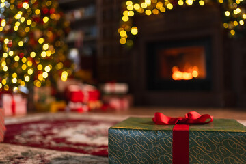 Obraz premium Green gift box in classical Christmas decorated interior living room library with fireplace. Christmas gift near fir tree on Christmas eve. Modern classic style interior design apartment. Christmas