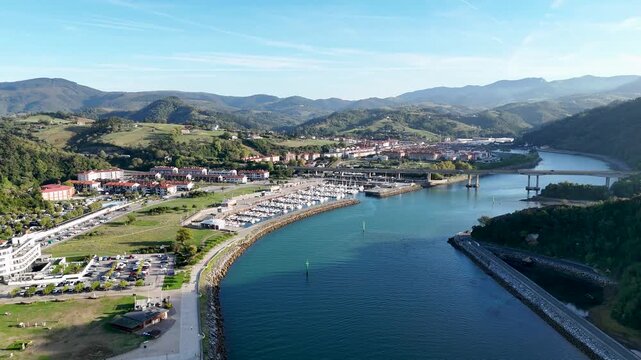 Aerial view of Antilla beach and the marina in Orio with boats docked along the estuary under a clear blue sky in Gipuzkoa, Basque Country, Spain.