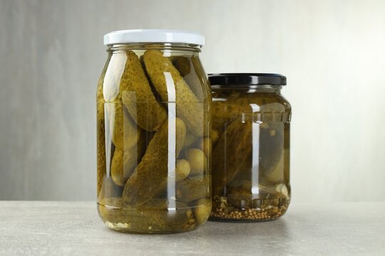 Pickled cucumbers in glass jars on grey table