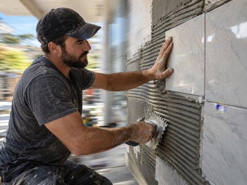 Tiler Spreading Adhesive on Wall Tiles