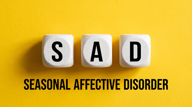Seasonal affective disorder sad concept with letter blocks on bright yellow background.