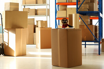 Fototapeta premium Shelves with many cardboard boxes and adhesive tape in warehouse