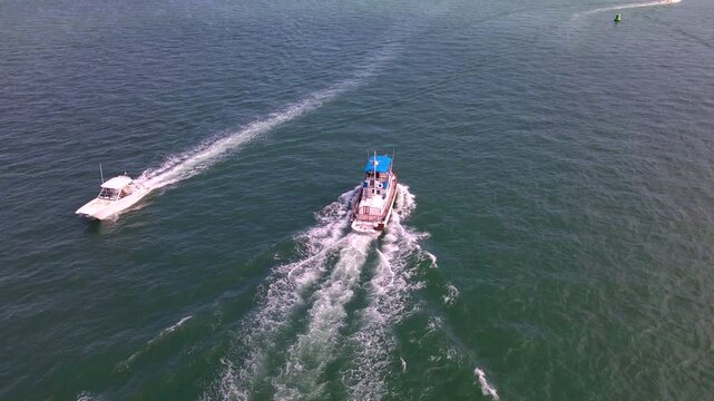 Two motorboats pass on different courses beside a green navigation buoy near Morehead City.
