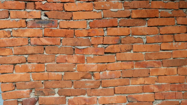 A background of aged, hand-laid, fired brick. Uneven terracotta-colored rows featuring traces of gray mortar, chipped edges, and deep cracks. An ideal texture for urban design.