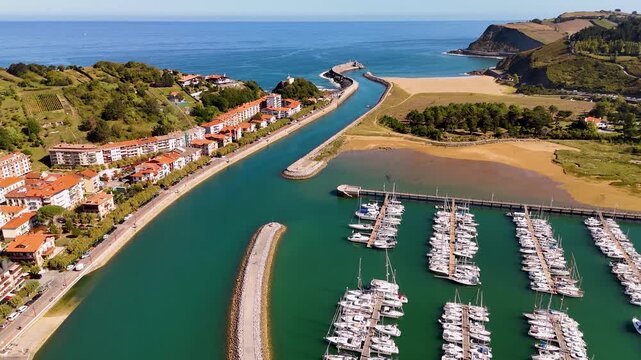 Aerial view of the marina with numerous boats docked in the harbor, surrounded by coastal buildings and green hills in Zumaia, Basque Country, Spain.